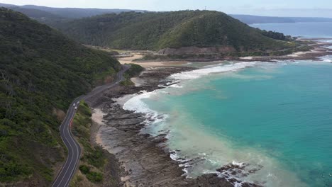 Iconic-Great-Ocean-Road-aerial-view-with-Teddy's-Lookout-hill-in-background,-Victoria,-Australia