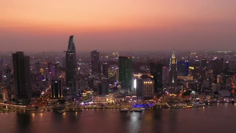 Ho-Chi-Minh-Stadt,-Ikonische-Skyline-Vietnams-Und-Luftpanorama-Am-Ufer-Des-Saigon-Flusses-An-Einem-Geschäftigen-Abend-Mit-Allen-Wichtigen-Gebäuden,-Die-Vor-Dem-Wunderschönen-Farbigen-Himmel-Beleuchtet-Sind