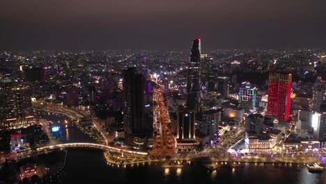 Ciudad-De-Ho-Chi-Minh,-Horizonte-Icónico-De-Vietnam-Y-Panorama-Aéreo-Frente-Al-Río-Saigon-En-Una-Noche-Ocupada-Con-Todos-Los-Edificios-Clave-Iluminados-Con-Luces-De-Colores