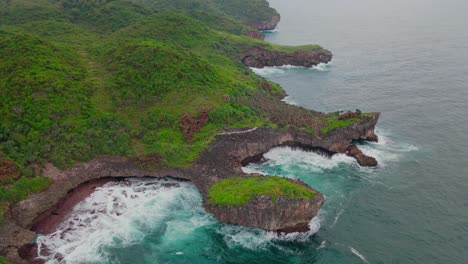 Aerial-view-of-rocky-coastline-of-an-island-that-overgrown-by-dense-of-trees