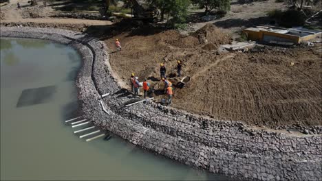 Drohnenansicht-Von-Bauarbeitern,-Die-Erde-Bewegen,-Um-Einen-Künstlichen-Teich-Zu-Bauen