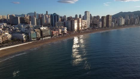 Aerial-panning-right-view-revealing-set-of-beachfront-skyscrapers-of-Benidorm-at-sunrise