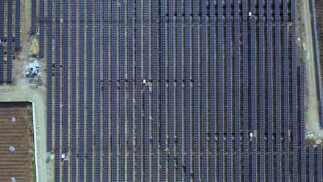 Top-view-of-blue-shiny-solar-photo-voltaic-panels-system-producing-renewable-clean-energy-Landscape-background,-4k,-aerial-video,-aerial-view-when-moving-top-with-moving-sideways,-slider-aerial-shoot
