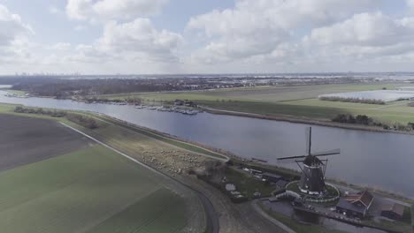 Drone-shot-of-Dutch-landscape-with-beautiful-windmill-and-small-harbor-in-the-background