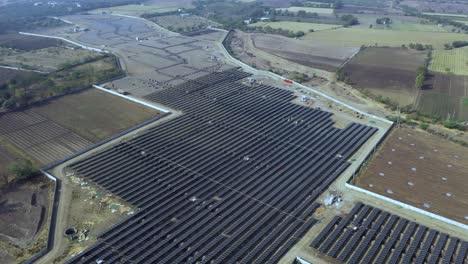 Part-of-ground-mounted-solar-power-station-with-fixed-photovoltaic-panels-next-to-the-spring-forest-in-overcast-weather,-aerial-view-when-moving-sideways,-Birds-eye-view-of-solar-plant,-4k-Aerial-View