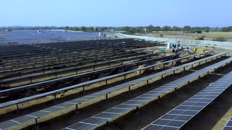 Enorme-Granja-Solar-De-Energía-Verde-Renovable-Con-Muchos-Paneles-Fotovoltaicos-En-Acres-De-Tierra-En-India,-Vista-Aérea-Cuando-Se-Mueve-La-Rotación-O-Hacia-Los-Lados,-4k,-Clips-De-Drones,-Punto-De-Vista-De-La-Planta-Solar-De-Rotación