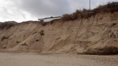 Coastal-erosion-of-Sandunes-on-Hemsby-Beach-with-house-on-the-Edge-of-a-cliff,-Wide-shot