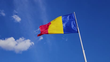 Bandera-Colorida-Ondeando-En-Un-Día-Soleado-Y-Ventoso,-Cielo-Azul,-Rumania