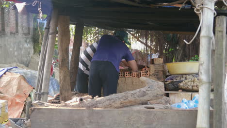 Alfareros-Vietnamitas-Retiran-Las-Figurillas-Cocidas-Después-De-Enfriarlas-Y-Las-Organizan-En-Contenedores,-Vista-Lateral-Mediana