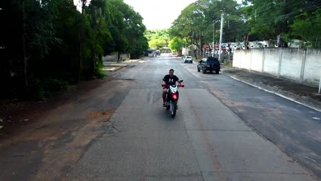 Seguimiento-Hacia-Atrás-De-Un-Joven-Montando-Motocross-En-Una-Carretera-Rural,-Paraguay