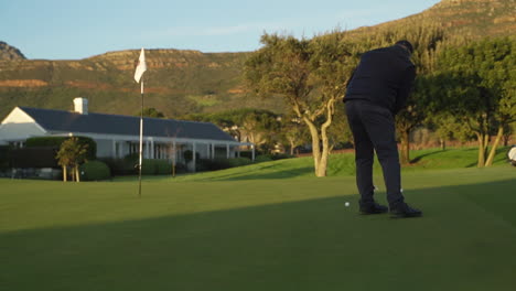 Golfer-Taking-Putt-on-the-Putting-Green-at-Sunrise-with-Mountains-in-the-Background