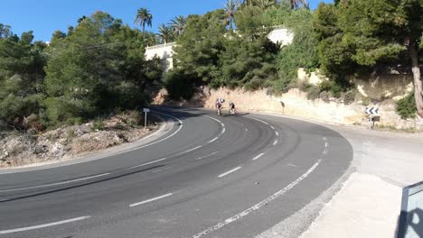 Cyclists-climbing-a-hill-in-Calpe-Spain,-winter-training