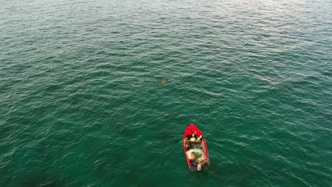 Drone-shot-of-father-in-fishing-boat-with-son,-and-daughter-snorkelling,-slow-motion