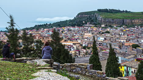 A-beautiful-young-woman-at-a-scenic-overlook-of-Corleone,-Sicily-Italy---time-lapse