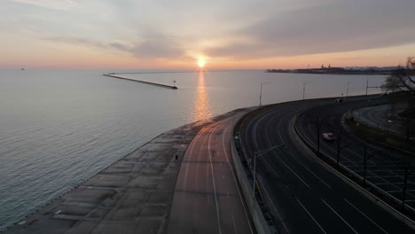 Aerial-view-following-a-man-running-on-the-Lakefront-Trail,-sunrise-in-Chicago,-USA