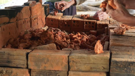 Medium-view-of-Vietnamese-potters-remove-intricate-clay-animal-figurines-from-earthen-brick-bin