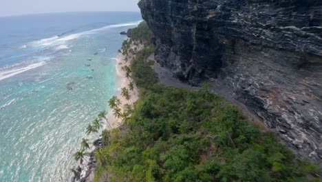 FPV-flight-along-rocky-cliffs-and-PLAYA-FRONTON-beach-in-LAS-GALERAS-SAMANA,-Dominican-Republic