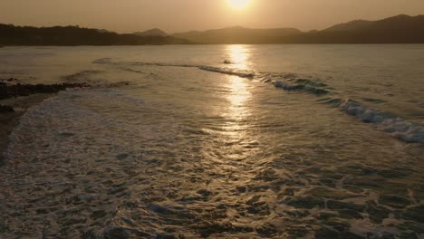 Rückwärtsaufnahme-Aus-Der-Luft-Von-Wunderschönen-Karibischen-Meereswellen-Und-Goldenem-Sonnenuntergang,-Der-Sich-Im-Wasser-Spiegelt---Strand-Von-La-Playita,-Dominikanische-Republik