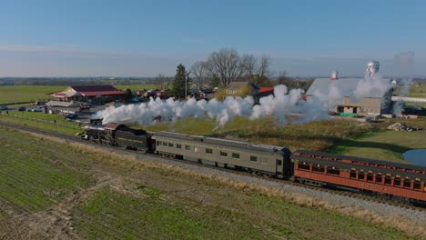 A-Drone-View-From-the-Side-of-an-Antique-Steam-Passenger-Train-Traveling-Thru-Farmlands-Blowing-Smoke-on-a-Sunny-Summer-Day