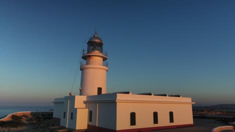 Drone-flying-past-person-and-Cavalleria-lighthouse-at-sunset