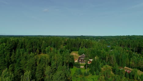 Drone-Levantando-Tiro-Inclinado-De-Casas-De-Vacaciones-Entre-Un-Bosque-Verde-En-Letonia
