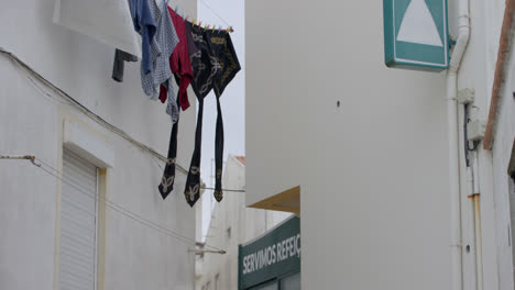 Laundry-hanging-to-dry-in-an-alleyway-in-the-town-of-Nazare,-Portugal_02