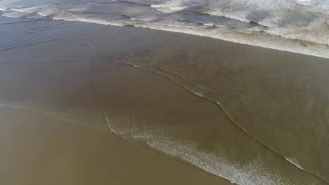 Krachende-Wellen-An-Einem-Strand-In-Neuseeland,-Blauer-Himmel-Und-Dunkler-Sand