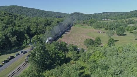 A-Drone-Above-and-Chasing-View-of-a-Doubleheader-Steam-Passenger-Train,-Traveling-Thru-Rural-Pennsylvania-on-a-Sunny-Summer-Day
