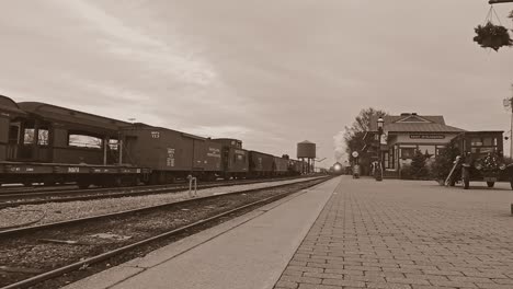 Una-Vista-En-Blanco-Y-Negro,-Sepia,-Del-Antiguo-Tren-De-Pasajeros-De-Vapor,-Con-Un-ángulo-De-Cámara-Bajo,-Llegando-A-Una-Estación-De-Tren,-Soplando-Humo-En-Un-Día-De-Invierno