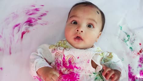 infant-paying-holi-in-traditional-dress-with-colors-from-top-angle