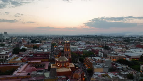Aerial-view-rising-over-the-Templo-de-San-Francisco-church,-dusk-in-Queretaro-city,-Mexico
