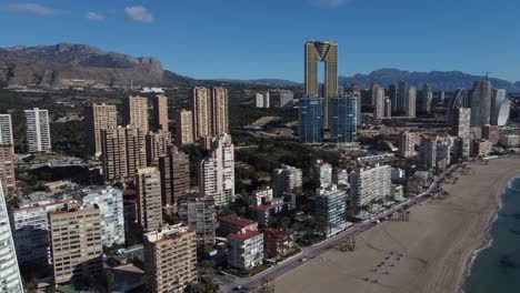 Circular-drone-flight-shows-the-cityscape-of-Benidorm-on-the-Mediterranean-Sea-with-its-skyscrapers-and-the-Puig-Campana-mountain
