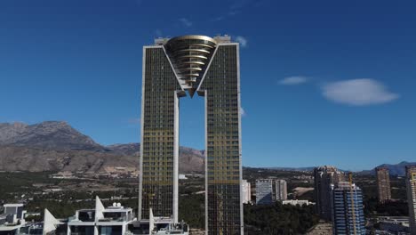 Aerial-view-of-modern-Intempo-Skyscraper-in-Benidorm-and-Puig-Campana-Mountain-in-background---Beautiful-sunny-day-with-blue-sky-in-Spain,-Valenciana