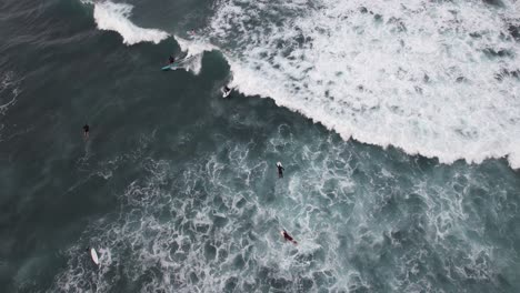 Top-Down-View-Of-Surfers-Catching-A-Wave,-Sea-Foam
