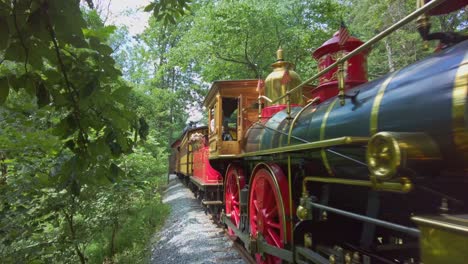 A-Restored-Antique-Steam-Engine,-Approaching-Close-Up-View,-Riding-Along-a-Single-Track-in-the-Woods-on-a-Sunny-Day