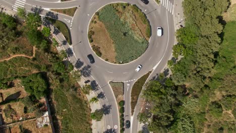 Vehicles-driving-around-roundabout-in-rural-Spain-landscape,-aerial-top-down-view