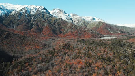 Aerial-view-of-snowy-mountains-with-vegetation-on-base-in-autumn-season