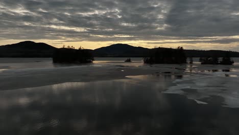 Sunset-beyond-calm-frozen-lake-Winter-Aerial
