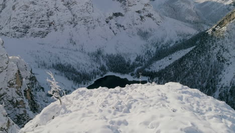 Atemberaubende-Luftaufnahmen-über-Schneebedeckten-Bergklippen-Offenbaren-Den-Abgeschiedenen-Pragser-Wildsee,-Den-Dolomitensee-In-Südtirol