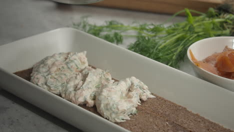 Chef-adds-first-layer-filling-to-Smorgastarta,-Salmon-and-dill-nearby