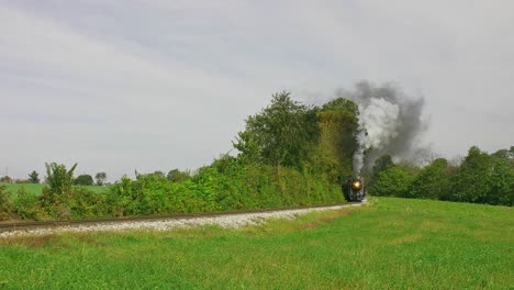 An-Antique-Steam-Passenger-Train-is-Approaching-Coming-Around-a-Curve,-Blowing-Lots-of-Smoke-and-Steam-on-a-Early-Fall-Day