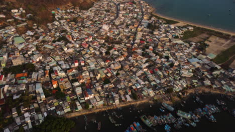 Aerial,-overcrowded-cramped-rural-slum-housing-next-to-ocean-coast-in-Southeast-Asia