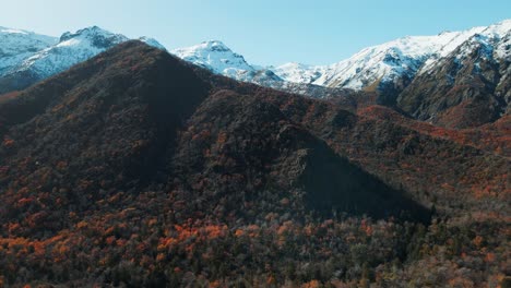 Aerial-establishing-shot-of-snowy-mountains-with-autumn-vegetation-on-base-in-Chile