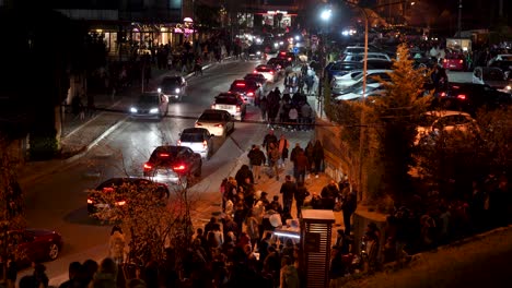 Belebte-Tirana-Straße-Bei-Nacht:-Eine-Menschenmenge-Von-Fußgängern,-Die-Inmitten-Des-Dichten-Verkehrs-Spazieren-Gehen
