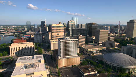 Aerial-view-of-the-sunlit-downtown-of-Nashville-and-Cumberland-river,-golden-hour-in-USA---pan,-drone-shot