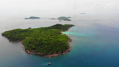 Aerial-High-Altitude-View-of-Beautiful-Wild-Green-Tropical-island,-Phu-Quoc-Vietnam,-Rocky-Coast,-Clear-Turquoise-Sea-and-Distant-islands-in-Horizon