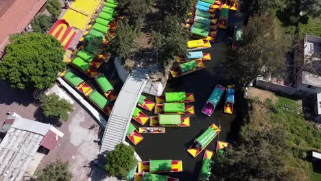 Aerial-Drone-Shot-of-colourful-boats-passing-through-Xochimilco-Water-Canal