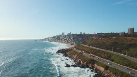 Aerial-view-following-scenic-Avenida-Borgoño-coastal-road-cityscape-alongside-Reñaca-ocean-waves