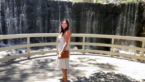 Attractive-Hispanic-woman-at-a-waterfall-overlook-smiles---slow-motion