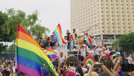 Camión-Blanco-Con-Escenario-Que-Lleva-A-Los-Artistas-Del-Desfile-Del-Orgullo-Más-Allá-De-Una-Gran-Multitud-A-Lo-Largo-De-La-Avenida-Juárez-Ondeando-Banderas-Del-Arco-Iris-En-La-Ciudad-De-México